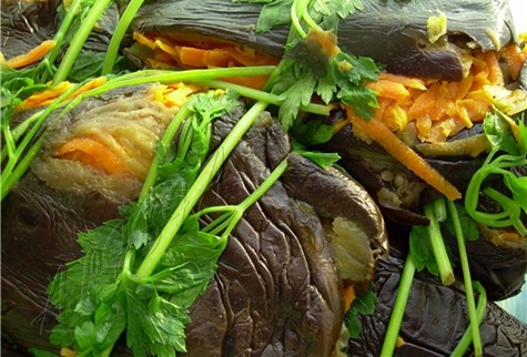 pickled eggplants with carrots, herbs and garlic on the table